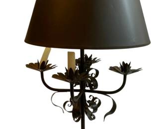 1166 - Wrought Iron Candelabra Style Table Lamp 26" (Description): Wrought iron candelabra style table lamp featuring ornate scrollwork throughout the base and stem. The lamp has four decorative flower-shaped bobeches extending from curved arms, with a central light socket. The piece displays elegant foliate and scroll motifs in a dark finish, topped with a dark tapered drum shade. Measures 26 inches tall. Used as is electric/electronic/mechanical item. No guarantee all components, untested.