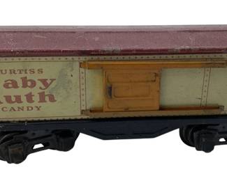 243 - Vtg Lionel O Train Car Post War Tin Metal (Description): Vintage Lionel O gauge train car from the post war era. This tin metal car features a Curtiss Baby Ruth Candy advertising livery and is marked as Lionel Lines No. 1679. The boxcar has a sliding door and sits on a black metal frame with four-wheel trucks. Measures 6 inches by 2 inches by 10 inches.
