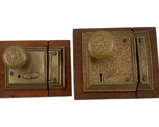 957 - 2pc. Lot Antique Brass Door Locks 6"x6.5" (Description): A two-piece lot of antique brass door locks. Each lock features decorative brass hardware with ornate knobs, mounted on wooden bases. The larger lock measures approximately 6 inches by 6.5 inches.