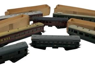 271 - Group Lot of 7 Marklin Train Cars 2"x2"x9" (Description): The collection includes passenger cars and cargo cars in various colors including maroon, gray, and cream. Some retain their original cardboard boxes. Each car measures approximately 2 inches by 2 inches by 9 inches.