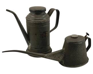 899 - 2pc. Lot Antique Metal Oil Cans 14" (Description): Two antique metal oil cans. The larger can features a cylindrical body with a long angled spout and curved handle, displaying a dark patina with areas of wear. The smaller can has a textured diamond pattern body with a short spout, side handle, and thumb-operated lever mechanism on the lid. Larger measures 14 inches tall.