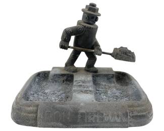 610 - Cast Iron Iron Firemen Ashtray Rehberger (Description): Cast iron ashtray marked Iron Firemen, manufactured by the A.C. Rehberger Company. Features a figural fireman shoveling coal atop a rectangular base with dual ash trays. Measures 5 inches by 6.5 inches by 4 inches.
