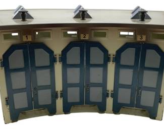 374 - Marklin Germany Metal 3 Stall Locomotive (Description): Marklin Germany metal 3 stall locomotive roadhouse. This model train accessory building features three numbered stalls with hinged double doors and decorative roof vents, designed to house locomotives. Measures 5" x 18" x 14".