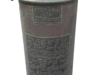 402 - The Columbia Metal Vtg Fire Extinguisher (Description): The Columbia metal vintage fire extinguisher. This classic fire safety device features embossed text indicating it was tested to 350 pounds, with instructions to turn upside down for use. The extinguisher retains its original nozzle and handle mechanism. Measures 23 inches tall.
