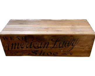 1065 - Vtg American Lady Shoes Wood Crate (Description): Vintage American Lady Shoes wood crate featuring stenciled advertising text reading "Wear American Lady Shoe" with decorative flourishes. This rustic wooden shipping crate would have been used to transport shoes from the manufacturer. Measures 12.5 x 39" x 15.5".