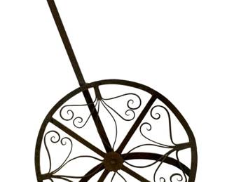 54 - Hand Forged Antique Wrought Iron Broiler (Description): Hand forged antique rotating broiler crafted from wrought iron. This utilitarian kitchen implement features a circular wheel design with decorative scrollwork and a long handle terminating in a ring for hanging. The broiler rotates to allow for even cooking over an open hearth or fire. Measures 4 inches by 33 inches by 17 inches.