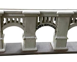 212 - Hand Crafted Train Bridge 8"x33"x4" (Description): Hand crafted train bridge featuring classical architectural details with arched openings and columned supports. The piece displays a balustrade along the top and appears to bear the name "Lackawanna" on one arch. Measures 8" x 33" x 4".