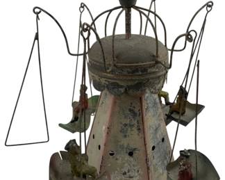 691 - Vtg German Tin Toy Carousel Swing Set (Description): Vintage German tin toy carousel swing set featuring a central conical tower with decorative wire cage top and finial. The carousel includes multiple swing seats suspended by wire arms, with small painted figures on the swings. The piece displays original painted finish with charming age-related patina. Measures 11" x 10" x 10".