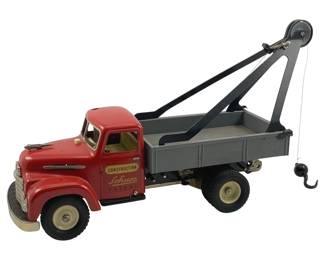 829 - Schuco Patent Construction Metal Tow Truck (Description): Schuco Patent metal tow truck from the Construction series. This vintage tin toy features a red cab with cream-colored interior, gray flatbed, and functioning crane mechanism with hook. The truck displays classic mid-century styling with detailed lithographed grille and