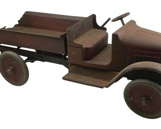 881 - Antique Keystone? Metal Truck 8"x24"x10" (Description): Antique metal truck, possibly Keystone brand. This pressed steel toy truck features a flatbed cargo area with raised sides, an open cab with steering wheel, front fenders, and rubber wheels with metal hubs. The truck displays an aged red-brown painted finish with natural patina consistent with its age. Measures 8 inches wide by 24 inches long by 10 inches tall.