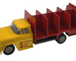 872 - Hubley Smiling Sam's Soda Truck 2"x5"x1.5" (Description): Hubley Smiling Sam's Soda Truck, a vintage diecast toy delivery truck featuring a yellow cab with "Smiling Sam's Soda" lettering on the door and a red compartmentalized cargo bed designed to hold miniature soda crates. The truck has rubber tires ansilver-painted details. Measures 2" x 5" x 1.5".