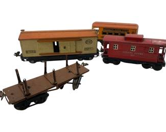 321 - Vintage Lionel Train Cars Lot of 4 (Description): Collection of four vintage Lionel train cars including a Lionel Lines No. 814 boxcar in cream and orange, a Lionel Lines 657 red caboose, an American Flyer Lines orange passenger car, and a brown flatcar with stake posts. The cars show age-appropriate wear consistent with play use. Each car measures approximately 4 inches by 3 inches by 10 inches.