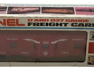 846 - Lionel Erie Bay London Caboose O Scale (Description): Lionel Erie Bay Window Caboose in O scale, presented in its original box. The caboose is numbered 9184 and features the Erie railroad livery with 'For Safety' and 'For Service Radio Equipped' markings. The box displays Lionel's 0 and 027 Gauge Freight Carrier branding with colorful locomotive imagery on the front panel.