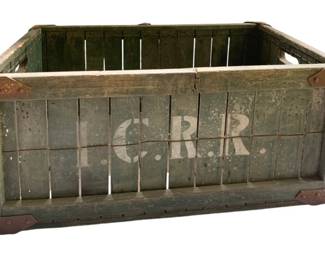 814 - I.C.R.R. Wood Crate 12"x26"x15" (Description): Vintage Illinois Central Railroad (I.C.R.R.) wooden crate featuring green painted finish with white stenciled lettering. The crate is constructed with slatted wood sides and metal corner reinforcements at both top and bottom edges. Cut-out handles are present on both ends for carrying. Shows authentic wear and patina consistent with age and use. Measures 12 inches by 26 inches by 15 inches.