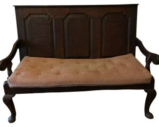 176 - Antique Wood Settle Bench w/Cushion (Description): Antique wood bench with cushion featuring a paneled high back with four arched panels. The bench has gracefully curved scrolled arms and stands on elegant cabriole legs. The dark wood frame is complemented by a tufted upholstered cushion seat in a warm tan geometric pattern. Measures 43 inches high by 55 inches wide by 24 inches deep.