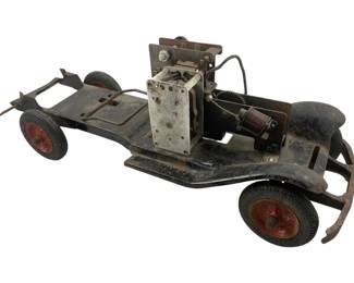 1039 - Antique Buddy L Mechanical Truck (Description): Antique Buddy L mechanical truck featuring an exposed motor mechanism and chassis. The truck displays original pressed steel construction with rubber tires on painted red wheel hubs. Measures 15 inches by 18 inches by 6 inches by 8 inches.