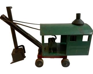 1043 - Antique Metal Toy Crane (Description): Antique metal toy crane featuring a working boom arm with bucket attachment. The toy has a cab structure mounted on a wheeled base, with painted finish showing age-appropriate wear consistent with its antique status.