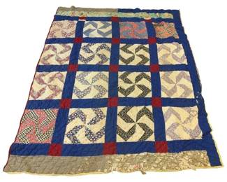 1154 - Vintage Pinwheel Pattern Quilt 76"x100" (Description): Vintage handmade quilt featuring a pinwheel pattern throughout. The quilt displays a grid of pinwheel blocks in various printed fabrics including florals, calicoes, and geometric prints set against cream-colored backgrounds. Blue sashing with red cornerstones frames each block. The backing appears to be a mix of patterned fabrics. Shows age-appropriate wear and losses consistent with use. Measures 76 inches by