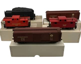 918 - 5pc Lot HO Scale Train Cars w/ Boxes (Description): A collection of five HO scale train cars with original boxes. The lot includes a red N.Y.C. caboose, a red Pennsylvania Caboose, a NYC coal car, and Pennsylvania railroad cars. Each car measures approximately 2 inches by 7 inches by 1.5 inches.