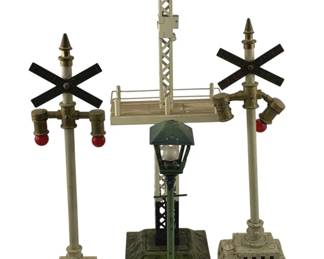 906 - 4pc Vintage O Scale Train Accessories 15" (Description): Collection of four vintage O scale train accessories measuring 15 inches. The lot includes two railroad crossing signals with X-shaped crossbuck signs and red warning lights on decorative bases, one lattice-style signal tower with platform, and one green cast iron street lamp. All pieces feature detailed construction typical of mid-century model train layouts.