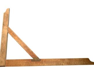 186 - Vtg Wood & Brass T Square (Description): Vintage wood and brass T square featuring a graduated ruler blade with engraved measurement markings. The tool displays a warm patina consistent with age and use, with brass hardware securing the perpendicular arm. A diagonal support brace connects the blade to the upright, providing stability for drafting work. This classic drafting instrument shows character from years of service.