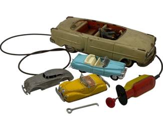 1131 - 4pc Lot Vtg Tin Lithograph Toy Cars (Description): A lot of four vintage toy cars including a large cream-colored tin lithograph convertible with remote control mechanism, a light blue convertible, a yellow tin litho car, and a small unpainted metal car body. The lot includes a wind-up key and remote control pump accessory. The toys show age-appropriate wear consistent with play use from the mid-20th century.