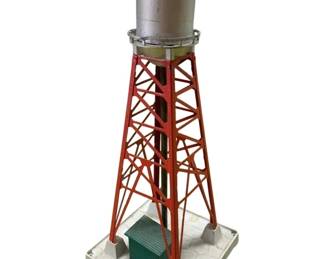 357 - Lionel #193 Industrial Water Tower 15"x6"x6" (Description): Lionel #193 Industrial water tower. This model railroad accessory features a metal construction with a silver tank atop an orange lattice tower framework, mounted on a gray base with a small green utility building. Measures 15 inches tall by 6 inches by 6 inches.