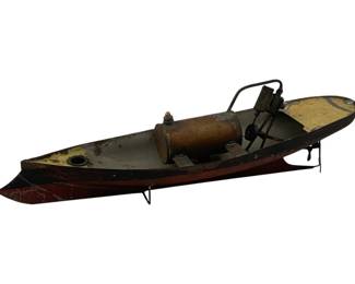 930 - Antique Steam Boat Toy 5"x16"x4" (Description): Antique steam boat measuring 5 inches by 16 inches by 4 inches. This vintage toy features a painted metal hull with a red bottom and gray upper body. The boat is equipped with a copper boiler and mechanical steam engine mechanism with propeller assembly at the stern. The vessel shows honest wear consistent with age and use, displaying its original painted finish throughout.