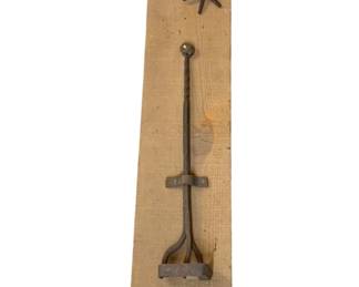 1160 - Antique Cattle Brand & Spur on Wood Board (Description): Antique cattle brand and spur display mounted on a rustic wooden board. The iron branding iron features the letter "E" at its end with a twisted shaft and decorative star-shaped finial at the top. A vintage rowel spur is also mounted above. The weathered wood plank serves as a decorative wall hanging piece. Measures 41 inches by 2.5 inches.