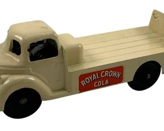 870 - Royal Crown Cola Metal Delivery Truck 2x5 (Description): Vintage Royal Crown Cola metal delivery truck in cream white finish with black rubber wheels. This pressed metal toy truck features the iconic Royal Crown Cola logo in red and white on the side panel, with a flatbed cargo area and raised tailgate. The cab features open window openings and a streamlined mid-century design. Measures 2 inches by 5 inches.