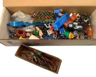 227 - Group Lot of Train Display Toys (Description): The collection includes an assortment of miniature plastic figures, vehicles, wagons, trees, bushes, fencing, a decorative lamp post, and various small-scale scenic elements suitable for model train layouts. Also included is a small box containing wiring and miniature light bulbs for display lighting.