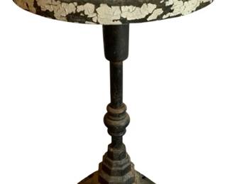 154 - Cast Iron Base Wood Top Table 19.5"x11" (Description): Vintage cast iron base table with round wood top. Features a decorative turned pedestal on a stepped octagonal base with raised lettering. The top shows heavily distressed paint with visible cream and dark layers, lending rustic character. Measures19.5 inches in height by 11 inches in diameter.