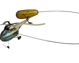 759 - Helibus Tin Litho Helicopter Toy (Description): Helibus tin lithographed helicopter toy featuring a white and teal blue body with a yellow overhead blimp-style attachment bearing the Helibus name. The toy includes a wire tether system for guided play, dual rotor blades, and landing wheels. Shows charming vintage wear consistent with age. Measures 4/6". Used as is electric/electronic/mechanical item. No guarantee all components, untested.