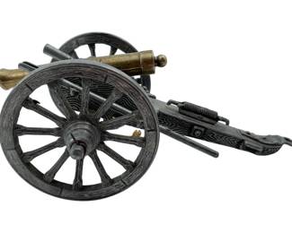 119 - Miniature Civil War Napoleon Cannon Model (Description): Miniature Civil War "Napoleon" cannon replica model featuring a brass barrel mounted on a detailed cast metal carriage with simulated wood grain texture. The carriage includes spoked wheels, trail handles, and decorative scrollwork details characteristic of period artillery pieces. Measures 3" x 7" x 4".