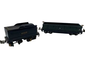 318 - 2 Lionel Train Cars 2"x3"x10" (Description): Two Lionel train cars measuring 2"x3"x10". The set includes a dark blue/black tender car marked "Lionel Lines" with a rounded top coal compartment, and a green gondola car. Both cars feature metal construction with working couplers and rolling ws, displaying vintage wear consistent with age and play use.