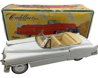 1179 - Cadillac 1950 Convertible Friction Car w/Box (Description): Cadillac 1950 convertible friction car with original box. This vintage tin toy features a white body with cream interior, chrome accents including bumpers, mirrors, and trim details. The friction-powered model represents a classic 1950s Cadillac open-top convertible. Accompanied by its original illustrated box depicting the Cadillac Open Type 1950 from the Fifties series.