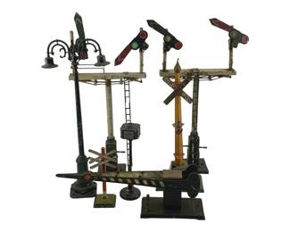 913 - Lot Vintage O Scale Train Accessories 7pc (Description): A lot of seven vintage O scale train accessories including various semaphore signals, signal bridges, a railroad crossing sign, a lamp post, and crossing gates. The pieces feature painted metal construction with working signal arms in various configurations, displaying characteristic wear consistent with age and use.