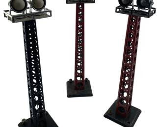 234 - Group Lot of 3 Railroad Flood Towers 12" (Description): Group lot of three railroad flood towers. Each tower features a lattice-style construction with a square base and dual flood lights mounted at the top. Towers measure 12 inches in height.