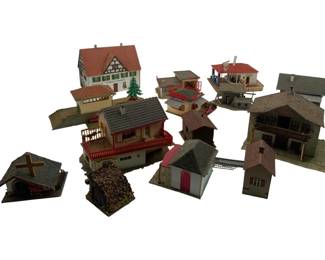 333 - Group Lot of HO Scale Train Display Buildings (Description): Group lot of train display items including assorted HO scale model buildings and structures. The collection features a variety of European-style architecture including half-timbered houses, chalets with balconies, a church or chapel, small outbuildings, a woodpile accessory, and commercial structures. Buildings are constructed of painted plastic and cardboard with detailed roofing and architectural features. Tallest