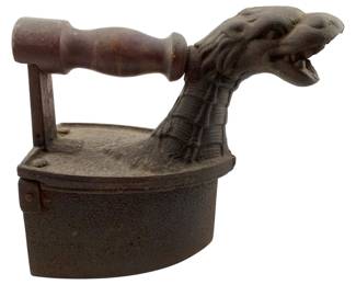99 - German Cast Iron Charcoal Iron w/ Dragon (Description): Antique German cast iron charcoal iron featuring a distinctive dragon head chimney. This unique pressing iron has a turned wooden handle mounted on a metal bracket and a hinged body designed to hold hot charcoals. The dragon chimney allowed heat and smoke to escape during use. The iron shows an aged patina consistent with its age. Measures 8.5" x 9" x 4.5".