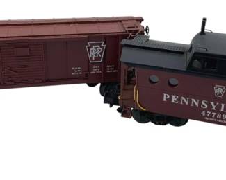 366 - Lot of 2 Pennsylvania Train Cars 4"x9"x3" (Description): Lot of two Pennsylvania train cars. The set includes a boxcar numbered 28647 and a caboose numbered 477899, both featuring the Pennsylvania Railroad (PRR) markings. Measures 4"x9"x3".