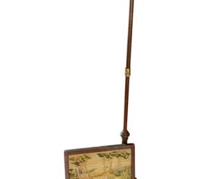45 - Needlepoint Tapestry Fire Screen w/ Stand (Description): Vintage needlepoint tapestry fire screen with wooden pole stand. The tapestry panel features a pastoral landscape scene with trees and foliage in soft colors. The screen mounts on a turned wooden pole with brass accents and stands on a tripod base. Needs repair. Measures 15" x 16.5", 52" H.