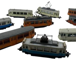 303 - Group Lot of 9 Hamo Train Cars 2"x2"x7" (Description): Group lot of 9 Hamo train cars. The collection includes various streetcar and trolley models in assorted colors. Each car measures approximately 2" x 2" x 7".