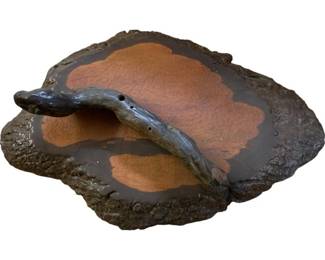 1110 - Organic Wood Wall Art Display 11"x36"x24" (Description): Distinctive wood wall art display featuring an organic, naturalistic form. The piece showcases a cross-section of wood with rich terracotta and burnt orange tones against a dark charcoal background, preserving the natural bark edge along the perimeter. A sculptural branch element rises from the surface, adding dimensional interest. The textured, crackled finish and irregular silhouette emphasize the natural character of