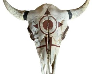 159 - Hand Painted Buffalo Skull 9"x22"x24" (Description): Hand painted buffalo skull featuring Native American-inspired geometric designs in reddish-brown pigment. The skull displays a central circular motif surrounded by triangular points creating a sun or star pattern, with additional linear designs extending down the nasal bridge. The horns show natural coloring with dark bands near the base. Measures 9" x 22" x 24".