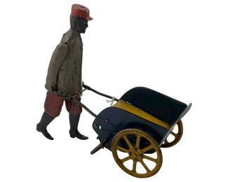 941 - Strauss Wind-up Tip-Top Tom 6"x6"x3" (Description): Strauss Wind-up Tip-Top Tom tin toy featuring a figure pushing a wheeled cart. This classic mechanical toy showcases the charming design typical of Strauss wind-up toys. Measures 6" x 6" x 3".