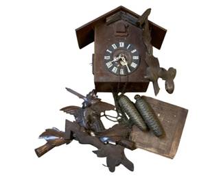 1152 - Wood Coo-Coo Clock AS IS 12"x12.5"x6" (Description): Wooden cuckoo clock in as-is condition. Features a carved wooden case with traditional Black Forest style bird and leaf decorations. The clock face displays Roman numerals with decorative hands. Includes two pine cone-shaped weights on chains. The elaborate carved crest features birds and foliage. Measures 12 inches by 12.5 inches by 6 inches. Sold as-is.