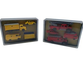 218 - Lot of Vtg Wiking Diecast Vehicle Sets (Description): Lot of vintage diecast model vehicles presented in two display cases. One set features yellow German postal service vehicles including trucks, a VW van, and a VW Beetle. The second set contains red fire service vehicles including fire trucks with ladders and emergency vehicles. The miniature vehicles appear to be HO scale German-made Wiking models, housed in plastic display cases with cork backing.