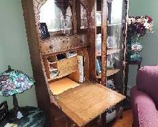 Oak slant top secretary desk with attached china closet. Curved front glass china closet, slant top desk with applied leaf and scroll design on lid, flat drawer, 2 beaded panel locking cupboard doors with applied leaf scroll mounts, serpentine drawer above desk, mirrored above serpentine drawer with leaf scrolled corners creating a single pigeon hole design, 44” top over desk and china closet, scrolled center, 75” high, Circa 1890