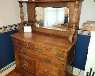 Oak Server – Serpentine front of serving surface with conforming locking divided drawer over single straight drawer and locking paneled cupboard at the bottom with applied opposing “C” scroll carving, quarter column corners, flat serpentine feet, beveled mirrored top with serpentine scrolls on top, crest with sunburst center, shelve supported on bulbous, fluted columns leading to molded scroll below, 75” high.